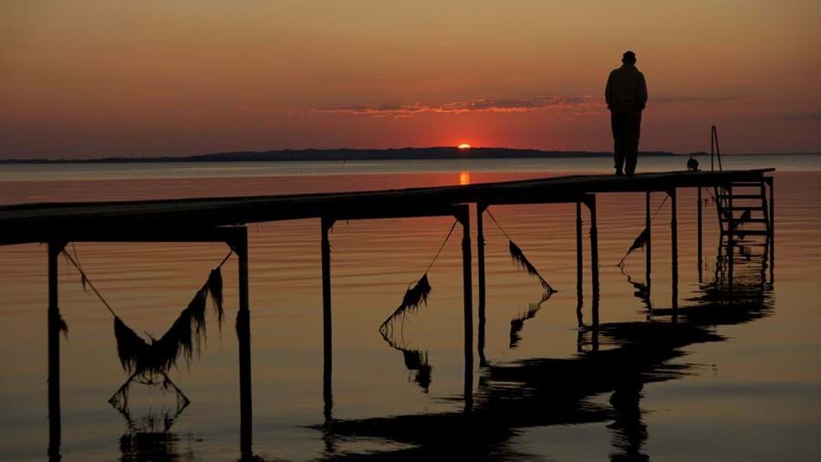 Man op steiger aan meer bij  rode zonsondergang in Denemarken