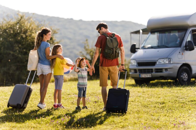 Happy family talking while going on a trip with camp trailer.